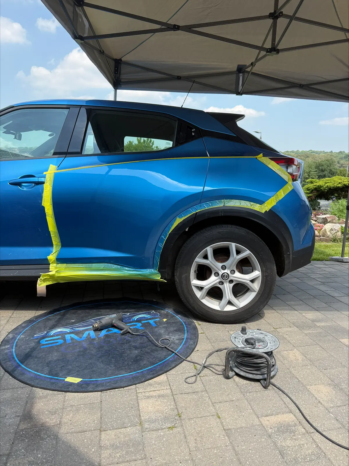 Blue car's rear quarter panel after repair, refinished and masked up
